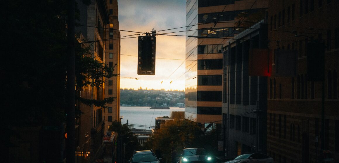 josh-hild-LuKMcTmGW_k-unsplash City street overlooking water at sunset, symbolising an urban weekend getaway.