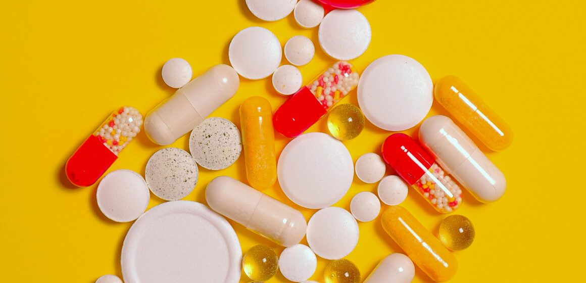 Person holding painkiller blister packs with a faint heart monitor graphic in the background
